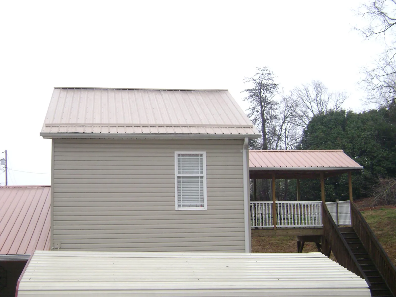 Tan metal roofs on a two story addition and attached porch, from a Roof Replacement job in Mililani