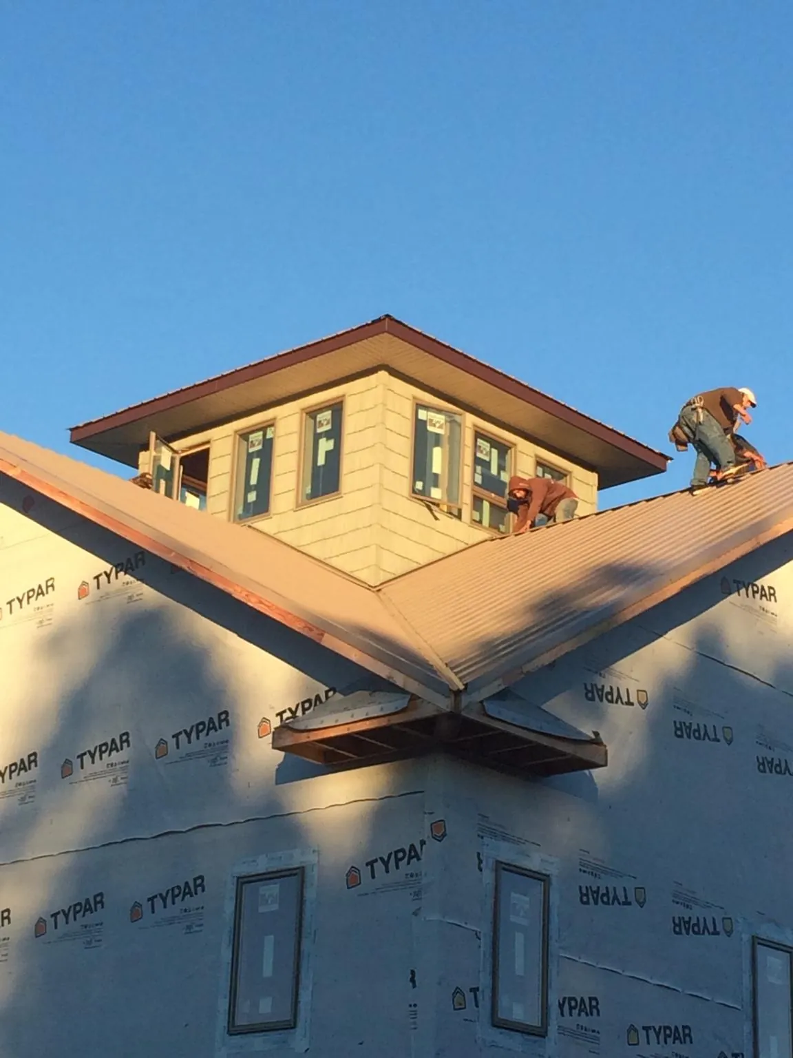 Roofers working around a rooftop cupola on a new metal roof at sunset — Roof Waterproofing in Mililani by Roofing Brothers